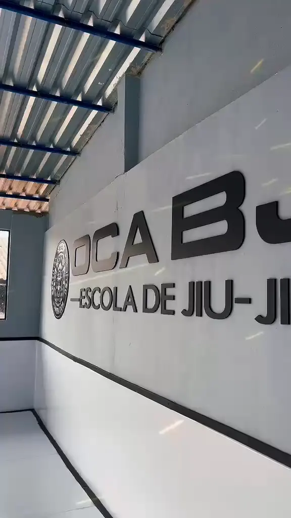 Parede da academia com o selo samurai e o letreiro OCA BJJ, Escola de Jiu-Jitsu