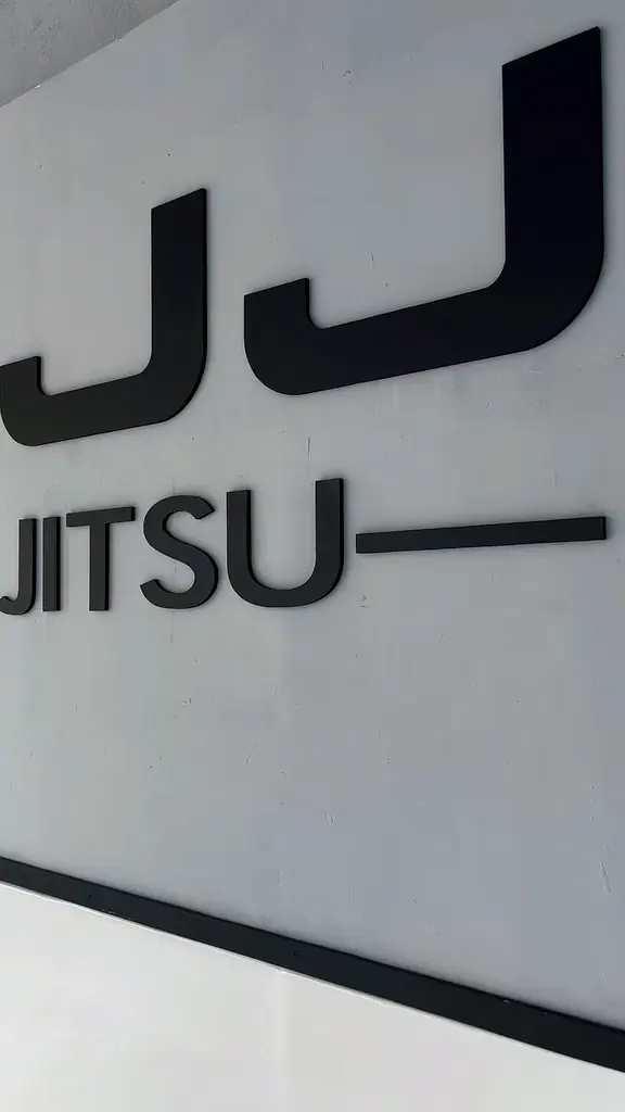 Detalhe do letreiro JIU-JITSU na parede branca da academia